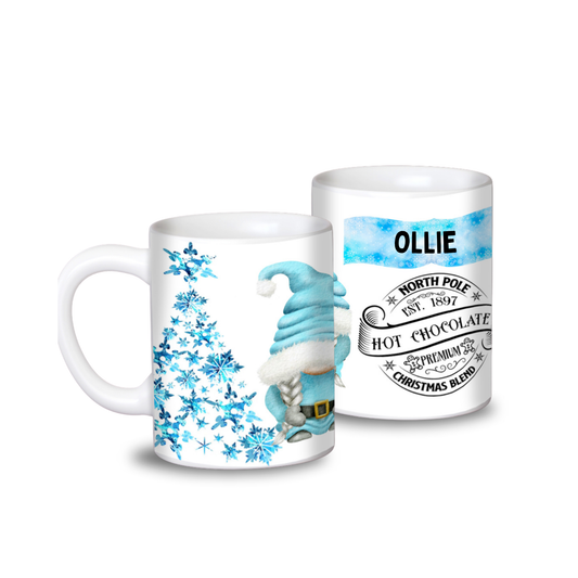 A ceramic mug with a Christmas themed design featuring a blue gonk, snowflakes, and personalized text including a name and 'North Pole Hot Chocolate'.